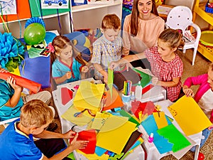 Kids holding colored paper and glue on table in