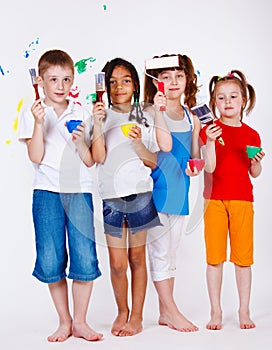 Kids holding paintbrushes and paints