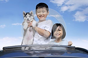 Kids and husky puppy on the sunroof photo