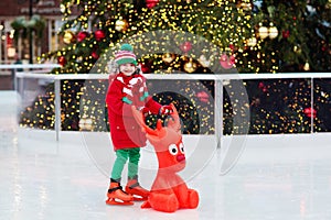 Kids ice skating in winter park rink. Children ice skate on Christmas fair. Little boy with skates on cold day. Snow outdoor fun