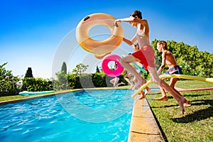 Kids with inflatable buoys jump dive into pool