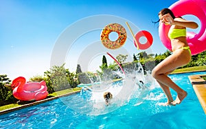 Kids with inflatable buoys splash dive into pool