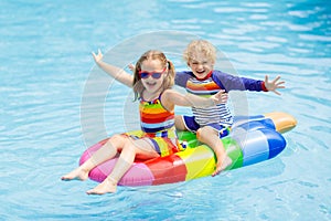 Kids on inflatable float in swimming pool.