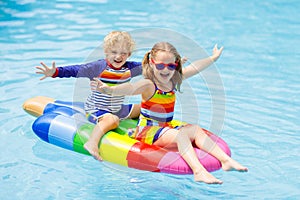 Kids on inflatable float in swimming pool.