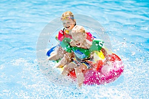 Kids on inflatable float in swimming pool.