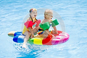 Kids on inflatable float in swimming pool.