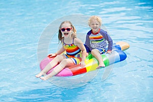 Kids on inflatable float in swimming pool.