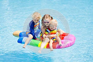 Kids on inflatable float in swimming pool.