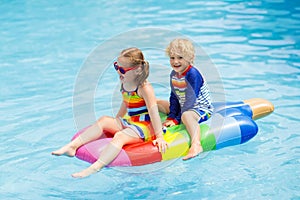 Kids on inflatable float in swimming pool.