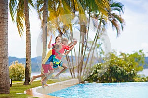 Kids jump into swimming pool. Summer water fun