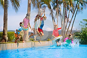 Kids jump into swimming pool. Summer water fun