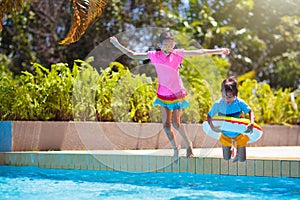 Kids jump into swimming pool. Summer water fun