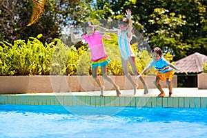 Kids jump into swimming pool. Summer water fun