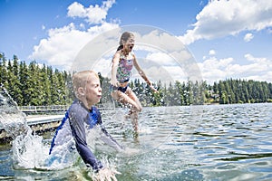 Kids jumping off the dock into a beautiful mountain lake. Having fun on a summer vacation