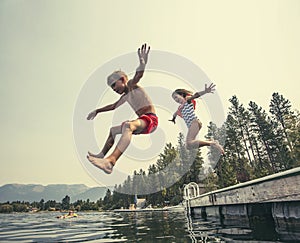 Kids jumping off the dock into a beautiful mountain lake