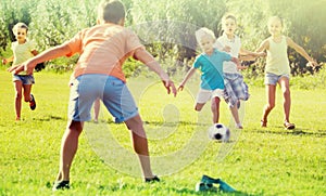 Kids kicking football in park