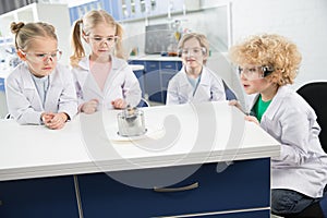 Kids in lab coats and protective glases making experiment