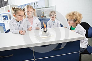 Kids in lab coats and protective glases making experiment