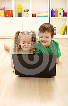 Kids with laptop laying on the floor