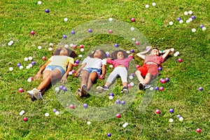 Kids lay in the grass and with color balls around