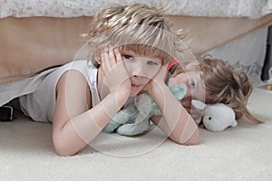 Kids laying on the floor with toys under the lights against a blurry background