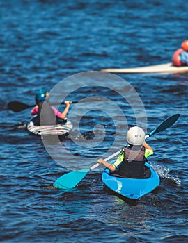 Kids learn kayaking, canoeing whitewater training in the lake river, children practicing paddling, yound kayakers in summer camp