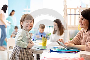 Kids learning arts and crafts in kindergarten with teacher