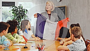 Kids learning together about france in geography class Female teacher showing french flag to kids in geography class