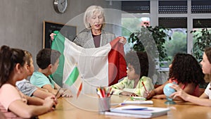 Kids learning together about italy in geography class Female teacher showing italian flag to kids in geography