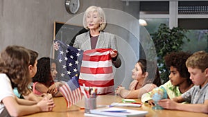 Kids learning together about usa in geography class Female teacher showing american flag to kids in geography class kids