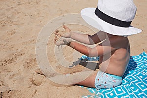 Kids lifestyle outdoor. Happy cute boy in panama playing with sand on the beach of sea. Summer vacation and family