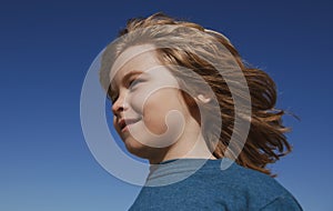 Kids looking away, close up head of cute child on blue sky with copy space.