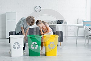 Kids looking trash cans with recycle