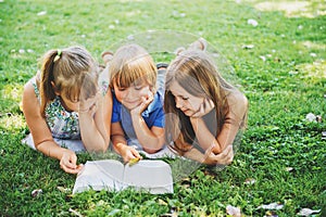 Kids lying on green grass and reading story book