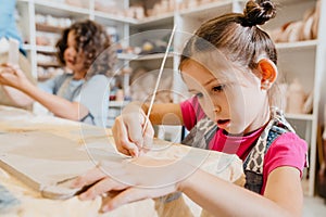 Kids making clay crafts while sitting at table in pottery class