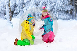 Kids making winter snowman. Children play in snow