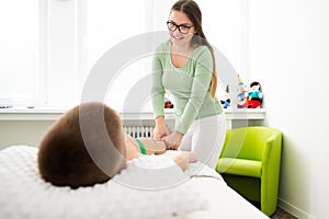 Kids massage concept background. Young female massage therapist giving a 6 year old boy leg massage. Physical therapy.