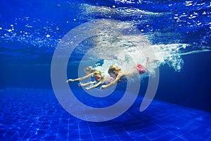 Kids with mother dive in swimming pool