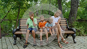 Kids with mother sitting on the bench and eating apples