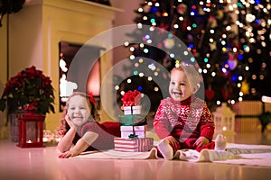 Kids opening Christmas presents at fireplace