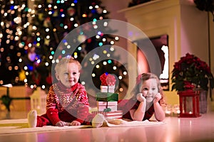 Kids opening Christmas presents at fireplace