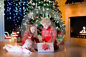 Kids opening Christmas presents at fireplace