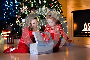 Kids opening Christmas presents at fireplace