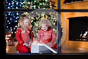 Kids opening Christmas presents at fireplace