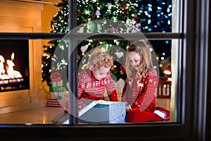 Kids opening Christmas presents at fireplace