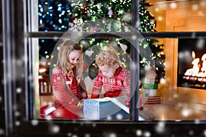 Kids opening Christmas presents at fireplace