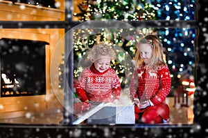 Kids opening Christmas presents at fireplace