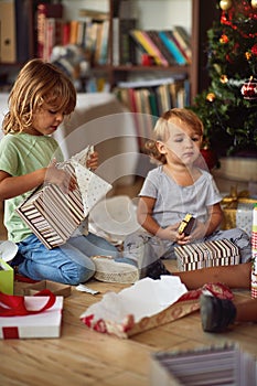 Kids opening Xmas presents. Children under Christmas tree with gift boxes