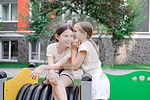 kids outdoors having fun on modern playground with new colorful equipment. sisterhood, friendship. two charming girls