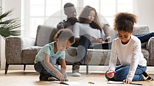 Kids painting in color books relaxing with parents at home